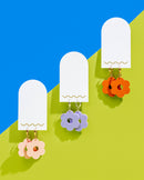 3 pairs of laser cut acrylic daisy hoop earrings on a bright blue and green background - locally made in NWA jewelry and earring workshops at Kaleidoscope Collective