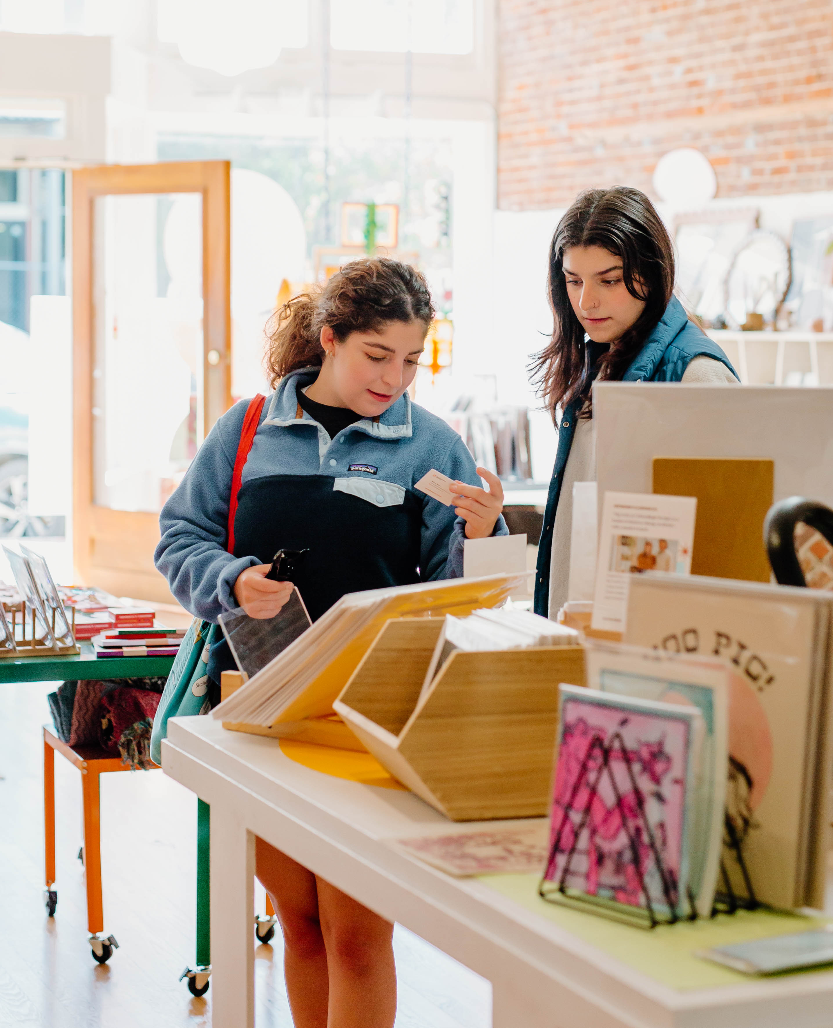 Two white women with brown hair looking at locally made products in retail space with colorful artwork. Locally Made Products, Handmade Products, Arkansas Artists Home decor art workshops 